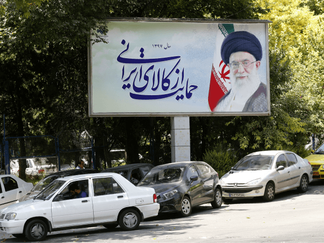 Cars drive by a poster depicting Iran's Supreme Leader Ayatollah Ali Khamenei in the capit