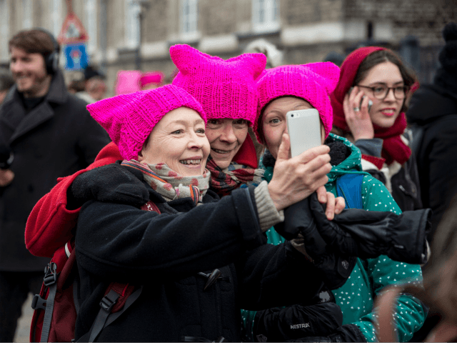 Women, wearing the so-called Pussy Hat, pose for a selfie during a rally to mark the Inter