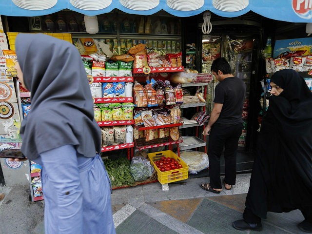 Iranians walk past a food shop in the capital Tehran on July 31, 2018. - Iran's currency t