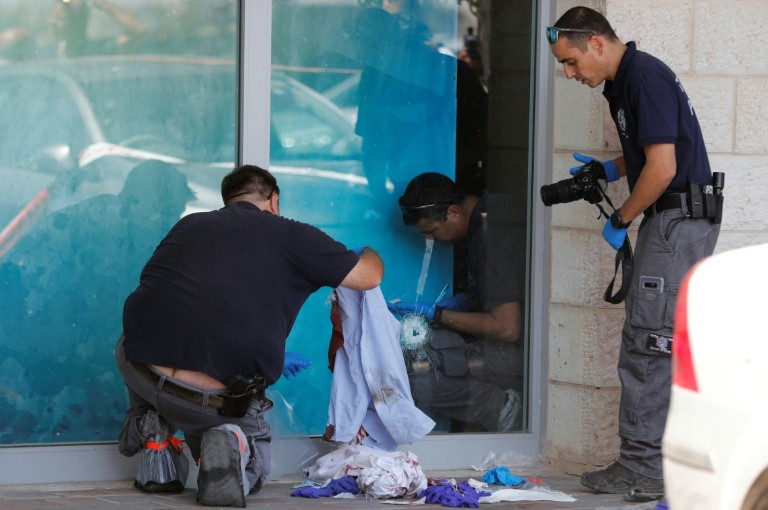 Israeli forensic policemen inspect the site where an Israeli man was fatally stabbed by a Palestinian near a mall at the Gush Etzion junction near Bethlehem in the occupied West Bank on September 16, 2018