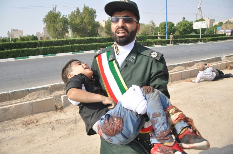 A member of Iran's elite Revolutionary Guards carries away a child wounded in a shooting rampage at a military parade in the southwestern city of Ahvaz that Foreign Minister Mohammed Javad Zarif blamed on a US ally in the region