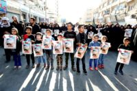 Iranian children hold pictures of a victim of Saturday's gun attack against a military parade in the southwestern city of Ahvaz, during a public funeral held on September 24