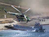 Russia War Games A Russian navy landing vessel unloads an armored vehicle as a military helicopter flies overhead during Russian military maneuvers Vostok 2018 on the training ground "Klerk", about 50 kilometers (31 miles) south of Vladivostok, Russian Far East port, Russia, Saturday, Sept. 15, 2018. The weeklong Vostok 2018 maneuvers are the largest war games Russia ever had. (AP Photo/Sergei Grits) The Associated Press