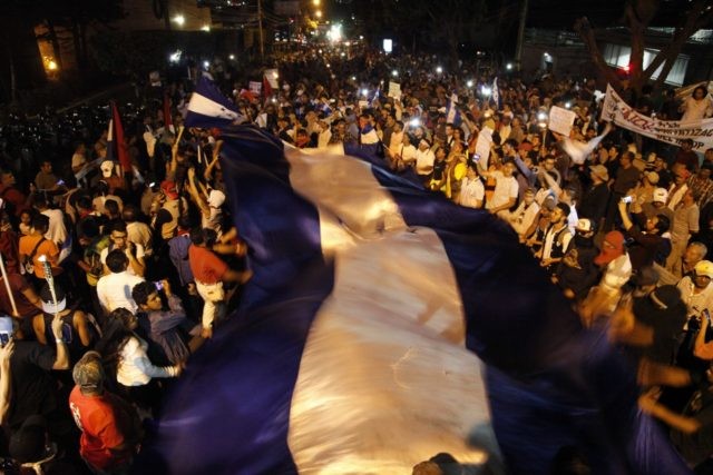 Hundreds of demonstrators with a Honduran flag protest in favor of the caravan of migrants who are currently stuck on the Guatemala-Mexico border, in front of the American embassy, in Tegucigalpa, Honduras, Friday, Oct. 19, 2018. A U.S.-bound caravan that once totaled more than 3,000 Central American migrants looked to …