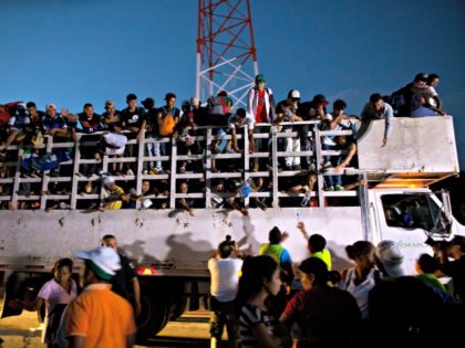 Men pass up water to Central Americans riding on the back of a truck while other migrants wait for rides, as a thousands-strong caravan of Central American makes its way toward the U.S. border, north of Pijijiapan, Mexico, at dawn on Friday, Oct. 26, 2018. Many migrants said they felt …