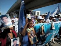 Members of a caravan of Central American mothers hold photographs of their disappeared children as they walk from their vehicles to the railroad tracks near what was once a migrant shelter in Lecheria on the outskirts of Mexico City, Friday, Oct. 26, 2012. The convoy, mostly comprised of women from …
