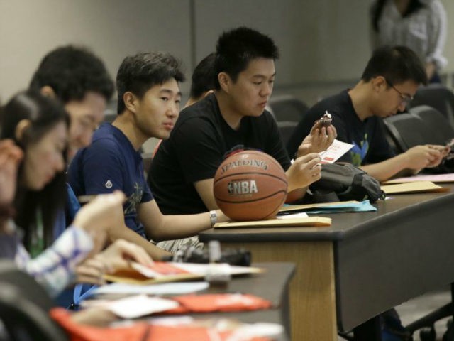 In this photo made Saturday, Aug. 22, 2015, Weikang Nie, a finance graduate student from China, sits which his basketball and fellow Chinese students during a new student orientation at the University of Texas at Dallas in Richardson, Texas. The U.S. Census Bureau research shows immigrants from China and India, …