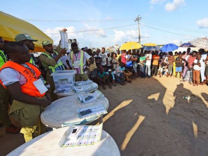 A picture taken on September 22, 2018 shows people watching as an electoral officer raises a ballot to count results in a ward after the Osun State gubernatorial election in Ede, near Osogbo, Osun State in southwest Nigeria. - The Osun election is seen as a litmus test for the …