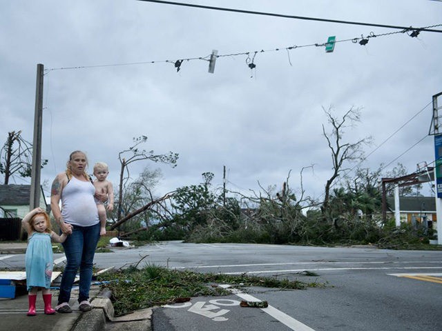 TOPSHOT - A woman and her children wain near a destroyed gas station after Hurricane Micha