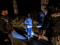 TOPSHOT - Italian police officers (L and R) newly dispatched at the border, check the papers of African migrants (C and Rear C-R hiding behind a bag) that walked towards the Italian side of the border after they were deposed by a French police van on the French side of …
