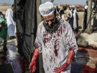 GettyImages-489749990 A South African Muslim, his jalabiya stained with blood from a bull, stands with others as they gathered during a ritual slaughter at a halal abattoir in Lenasia, 30km south of Johannesburg, for Eid al-Adha on September 24, 2015. The world's 1.5 billion Muslims is marking Eid al-Adha, the Feast …