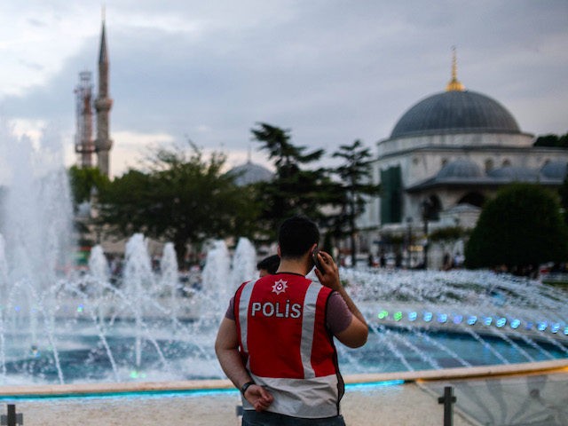 A Turkish police officer speaks on the phone as he stands guard by a fountain on June 6, 2