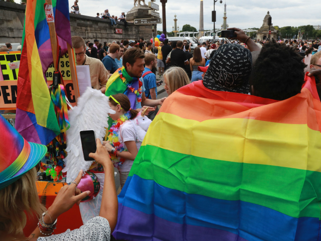 Activists wear rainbow flags as they take part in the Gay Pride parade in Paris on June 24