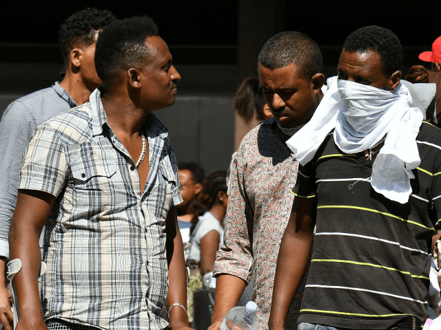 Refugees and asylum seekers wait after being displaced from a palace in the center of Rome