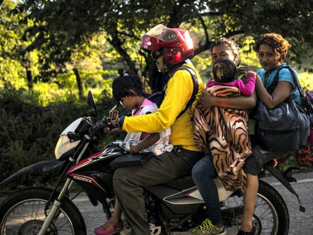 A Honduran migrant family heading in a caravan to the US, travels on a motorbike near Mapastepec, southern Mexico on October 25, 2018. - Thousands of Central American migrants crossing Mexico toward the United States in a caravan have resumed their long trek, walking about 12 hours to their next …