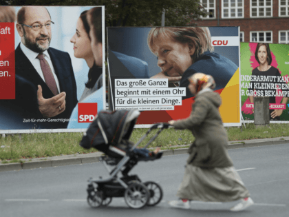BERLIN, GERMANY - SEPTEMBER 08: A Muslim woman pushes a pram past election campaign billboards that show German Social Democrat (SPD) chancellor candidate Martin Schulz (L), German Chancellor and Christian Democrat (CDU) Angela Merkel (C) and Greens Party co-lead candidate Katrin Goering-Eckardt on September 8, 2017 in Berlin, Germany. Germany …
