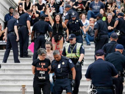 Activists are arrested by Capitol Hill Police officers after occupying the steps on the East Front of the U.S. Capitol as they protest the confirmation vote of Supreme Court nominee Brett Kavanaugh on Capitol Hill, Saturday, Oct. 6, 2018 in Washington. (AP Photo/Alex Brandon)