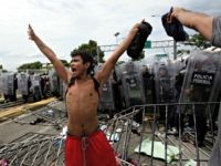 Migrant Caravan, Mexican Federales A youth calls for calm as he stands in from of a phalanx of Mexican Federal Police in riot gear, after Central American migrants rushed the gate at the border crossing in Ciudad Hidalgo, Mexico, Friday, Oct. 19, 2018. Central Americans traveling in a mass caravan broke through a Guatemalan …