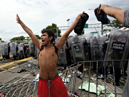 A youth calls for calm as he stands in from of a phalanx of Mexican Federal Police in riot