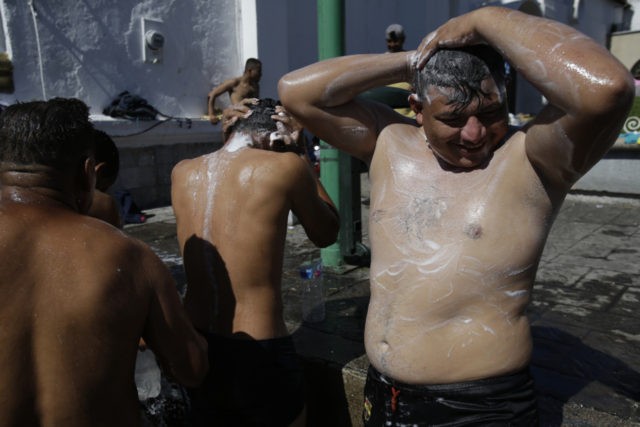Central American migrants making their way to the U.S. in a large caravan bathe using wate