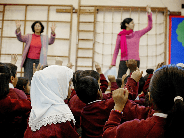 LONDON, UNITED KINGDOM: WITH 'RELIGIOUS EDUCATION A FESTIVAL OF LIGHT IN BRITAIN' A young girl wearing a muslim headscarf listens as two teachers instruct the class in singing christmas songs at Featherstone Primary school 09 December 2003 in Southall London. Sitting cross-legged the children intone a Sikh chant accompanied by …