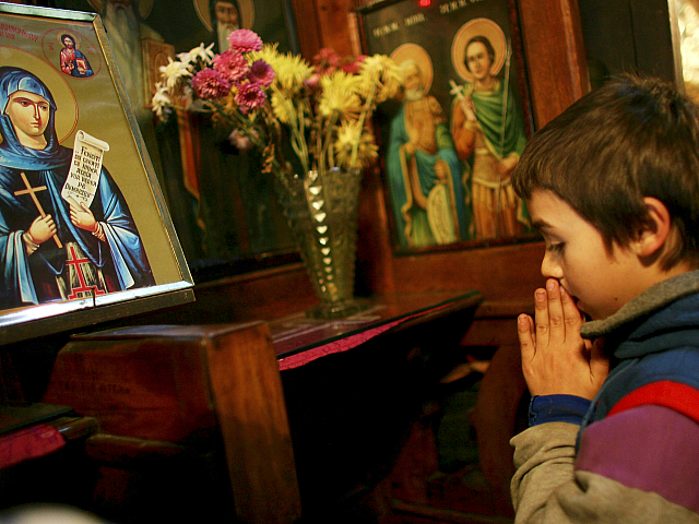 BUCHAREST, ROMANIA - DECEMBER 05: A homelss street child prays at an Orthodox church Decem