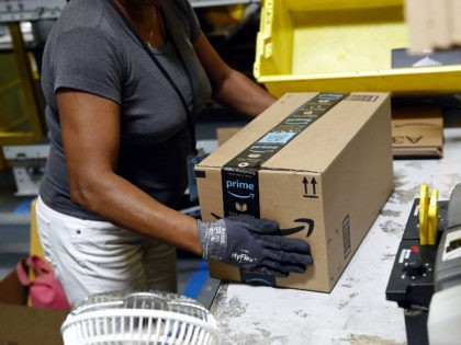 FILE- In this Aug. 3, 2017, file photo, Myrtice Harris applies tape to a package before shipment at an Amazon fulfillment center in Baltimore. Amazon is boosting its minimum wage for all U.S. workers to $15 per hour starting next month. The company said Tuesday, Oct. 2, 2018, that the …