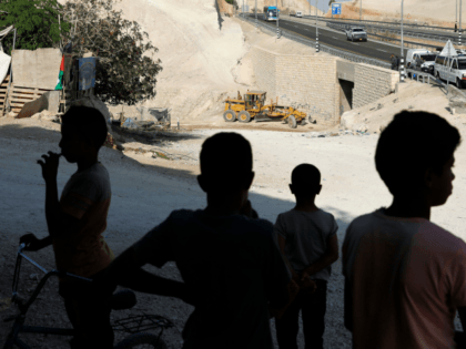 Bedouin children look at an Israeli army excavator in the Palestinian Bedouin village of Khan al-Ahmar, east of Jerusalem in the occupied West Bank on October 16, 2018. - Israel plans to demolish the Bedouin community, which it says was built illegally, despite international calls for a reprieve. (Photo by …