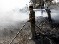 gaza fire Israeli soldiers attempt to extinguish a fire in a forest field near the Kibbutz of Nahal Oz, along the border with the Gaza Strip, on July 17 after it was caused by inflammable material attached to a balloon flown by Palestinian protesters from across the border. (Photo by MENAHEM KAHANA …