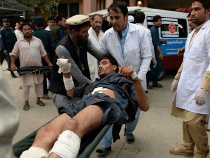 Afghan volunteers carry an injured youth on a stretcher to a hospital, following an attack that targeted a parliamentary election rally in the Kama district of the eastern province of Nangarhar, in Jalalabad on October 2, 2018. - At least 13 people were killed in a suicide attack on an …