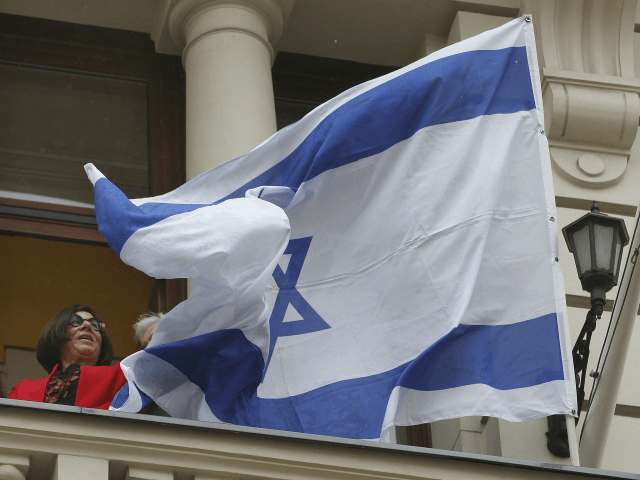Israeli Ambassador Anna Azari holds the Israeli flag from a balcony of the historic Bristol Hotel in Warsaw, Poland, during a ceremony on Tuesday, Oct. 23, 2018. The flag hanging was a re-enactment ceremony marking the 70th anniversary of Israel's first diplomatic outpost as a new nation at the same …