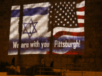 People walk under the US and the Israeli flags projected on the walls of Jerusalem old city on October 28, 2018, organised by Jerusalem municipality to show solidarity with the Pittsburgh Jewish community following the shooting attack at the Tree of Life synagogue in Pittsburgh, Pennsylvania. (Photo by Menahem KAHANA …