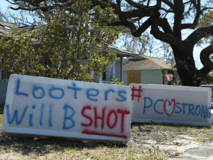 Signs reading, 'Looters Will B Shot' and '#PCStrong,' are seen written on mattress boxes in front of a home as people deal with the aftermath of hurricane Michael on October 13, 2018 in Panama City, Florida. The hurricane hit the Florida Panhandle as a category 4 storm causing massive damage …
