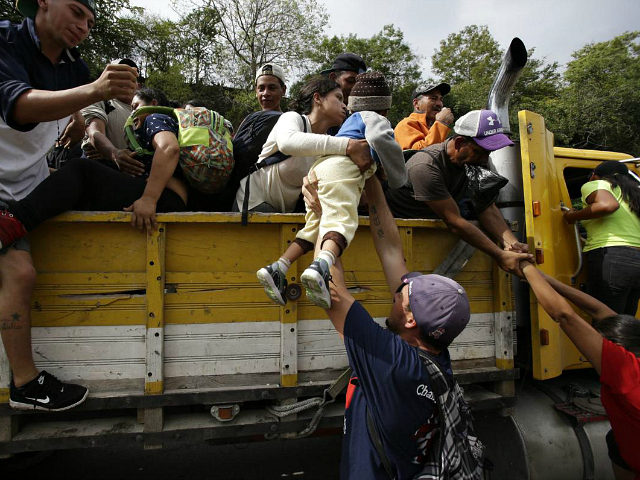 Honduran migrants bound to the U.S border climb into the bed of a truck in Zacapa, Guatema