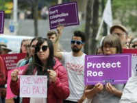 pro-abortion-rally-2018-naral-ap Hillary Namba, left, of Seattle, holds a wire coat hanger and a sign Tuesday, July 10, 2018, as she takes part in a protest in Seattle against President Donald Trump and his choice of federal appeals Judge Brett Kavanaugh as his second nominee to the Supreme Court. Kavanaugh plunged into …