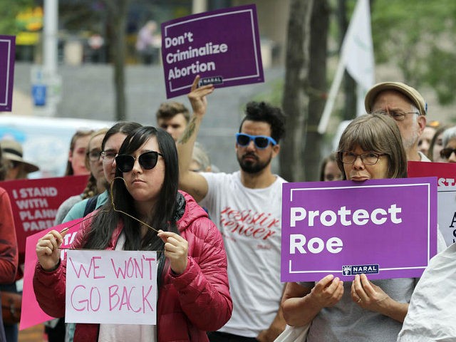 Hillary Namba, left, of Seattle, holds a wire coat hanger and a sign Tuesday, July 10, 201