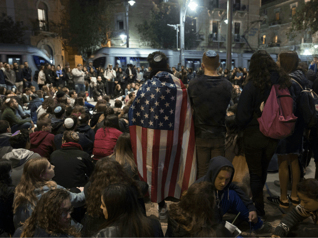 An Israeli man holds the US flag as youths gather in center Jerusalem on October 28, 2018,