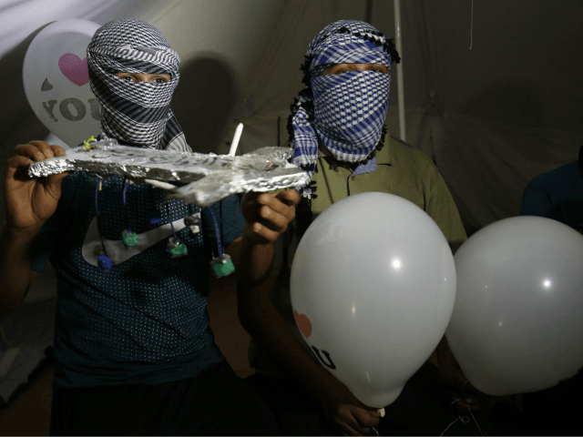 Masked Palestinian protesters calling themselves the 'night confusion units' hold incendiary devices attached to ballons to be flown towards Israel, near the Gaza-Israel border east of Rafah in the southern Gaza Strip, on September 26, 2018. - The border protests since March 30 have been labelled the 'Great March of …