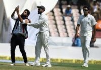 A fan invades the pitch to take a selfie and hug Indian cricket captain Virat Kohli (C) during the first day's play of the second Test against the West Indies
