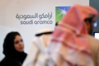 Investors stand in front of the logo of Saudi state oil giant Aramco during a January, 2016 forum in Riyadh