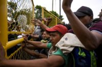 Mexican authorities have reinforced the metal gate holding back Honduran migrants after a previous group broke through a weaker barrier