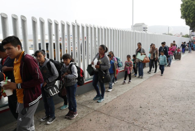 This July 26, 2018, file photo shows people lining up to cross into the United States to begin the process of applying for asylum near the San Ysidro port of entry in Tijuana, Mexico. Homeland Security's watchdog says immigration officials were not prepared to manage the consequences of its "zero â¦