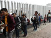 This July 26, 2018, file photo shows people lining up to cross into the United States to begin the process of applying for asylum near the San Ysidro port of entry in Tijuana, Mexico. Homeland Security's watchdog says immigration officials were not prepared to manage the consequences of its "zero …