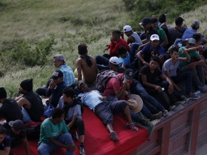 Migrants hitch a ride on the back of a truck as a thousands-strong caravan of Central Amer