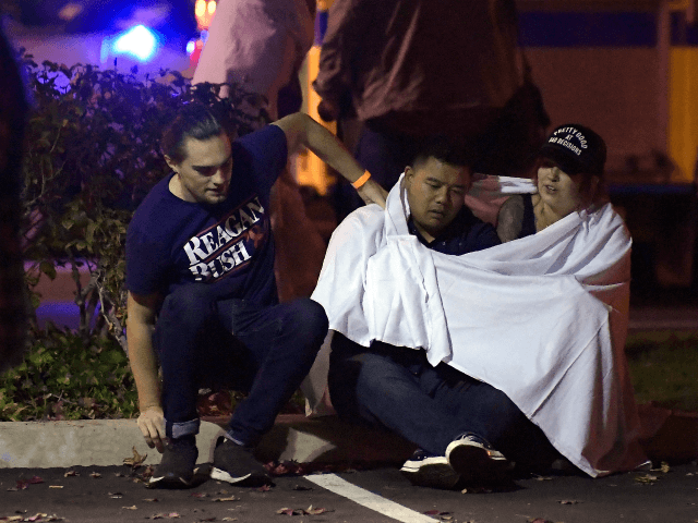 People comfort each other as they sit near the scene Thursday, Nov. 8, 2018, in Thousand Oaks, Calif. where a gunman opened fire Wednesday inside a country dance bar crowded with hundreds of people on "college night," wounding 11 people including a deputy who rushed to the scene. Ventura County …