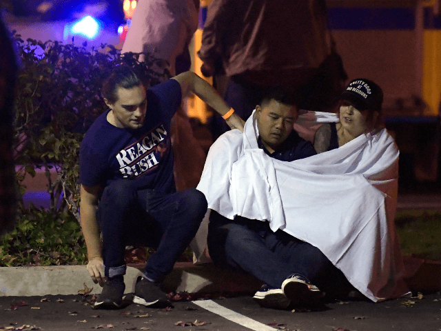 People comfort each other as they sit near the scene Thursday, Nov. 8, 2018, in Thousand O