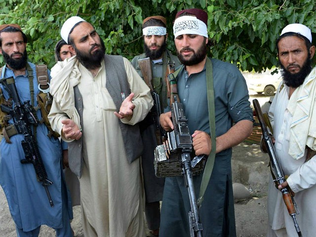 Afghan Taliban militants stand with residents as they took to the street to celebrate ceas