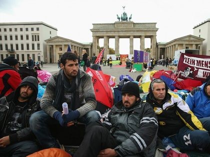 BERLIN, GERMANY - OCTOBER 17: Refugees from Iraq, Iran and Afghanistan keep warm on the 8th day of a hunger strike in front of the Brandenburg Gate on October 17, 2013 in Berlin, Germany. 28 refugees, some of whom have been in Germany for as long as seven years waiting …