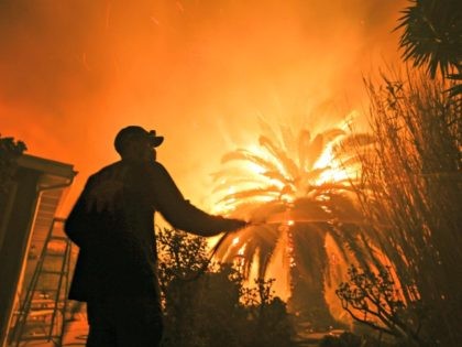 Park Billow, 27, sprays water on the hot spots in his backyard as the Woolsey Fire burns in Malibu, Calif., Friday, Nov. 9, 2018. Authorities announced Friday that a quarter of a million people are under evacuation orders as wind-whipped flames rage through scenic areas west of Los Angeles and …