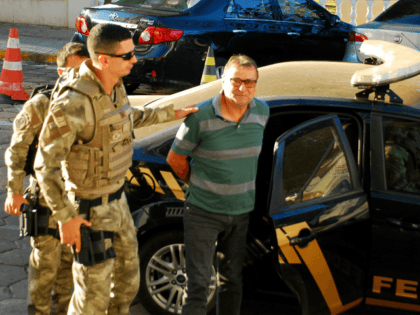 Italian ultra-leftist militant Cesare Battisti arrives escorted by police to the headquarters of the Federal Police in Corumba, Mato Grosso do Sul State, West of Brazil, on October 5, 2017, after a federal judge ordered his preventive detention. Brazilian police on on the eve detained Battisti, who was convicted of …